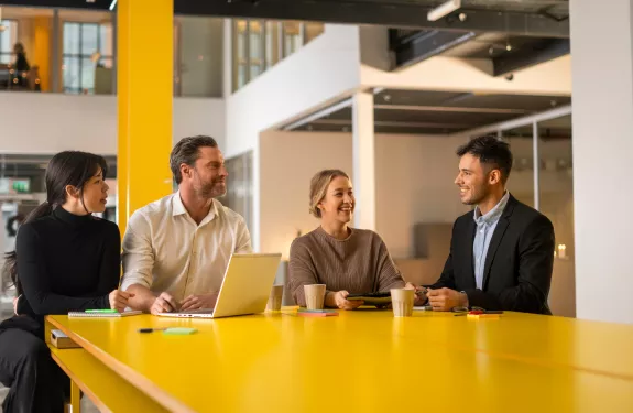 Four people collaborating at a yellow table