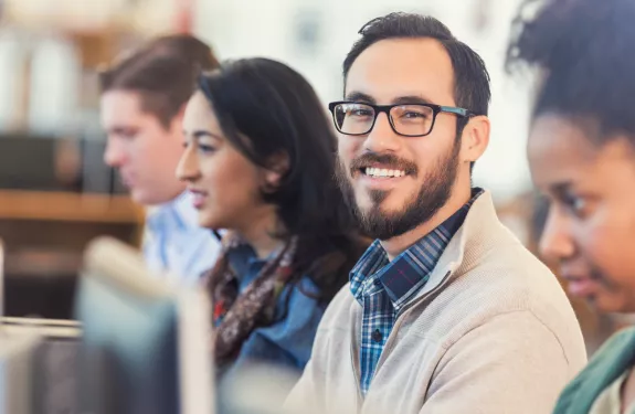 Man in glasses smiling by computer