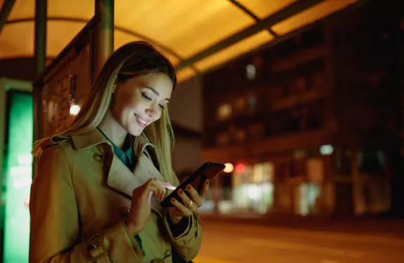 Woman at bus stop at night with phone