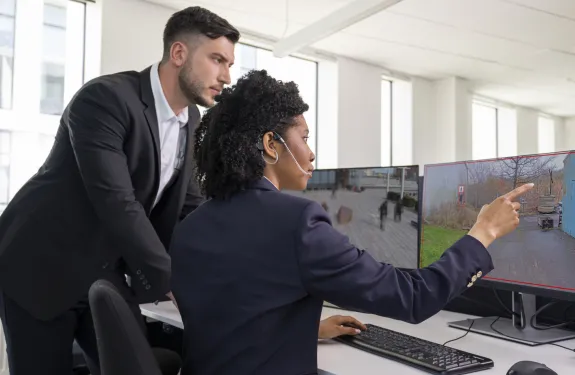Two people watching a computer screen using video analytic overlays