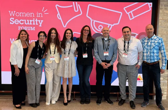 Axis staff stands in front of Women in Security Forum banner.