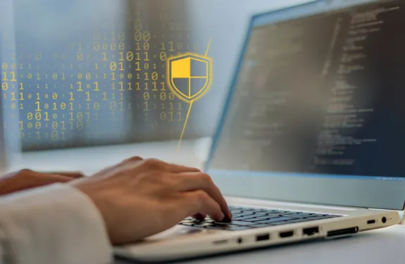 Person typing on computer, with an overlay of cybersecurity symbols.