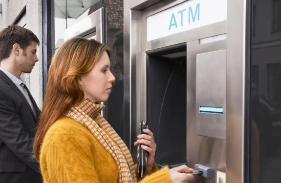 A woman inserts her card into an ATM