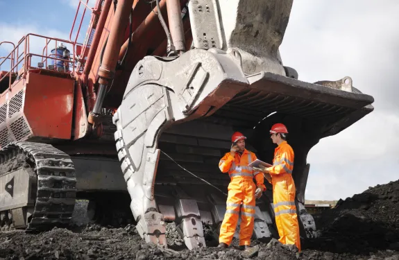 Miners standing on a mining site with a vehicle next to them
