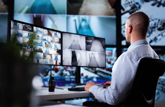 Man sitting in front of screens in a real time crime center (RTCC)