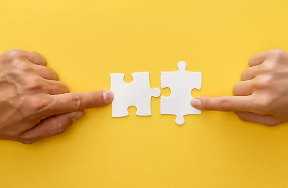 Two hands putting puzzle pieces together