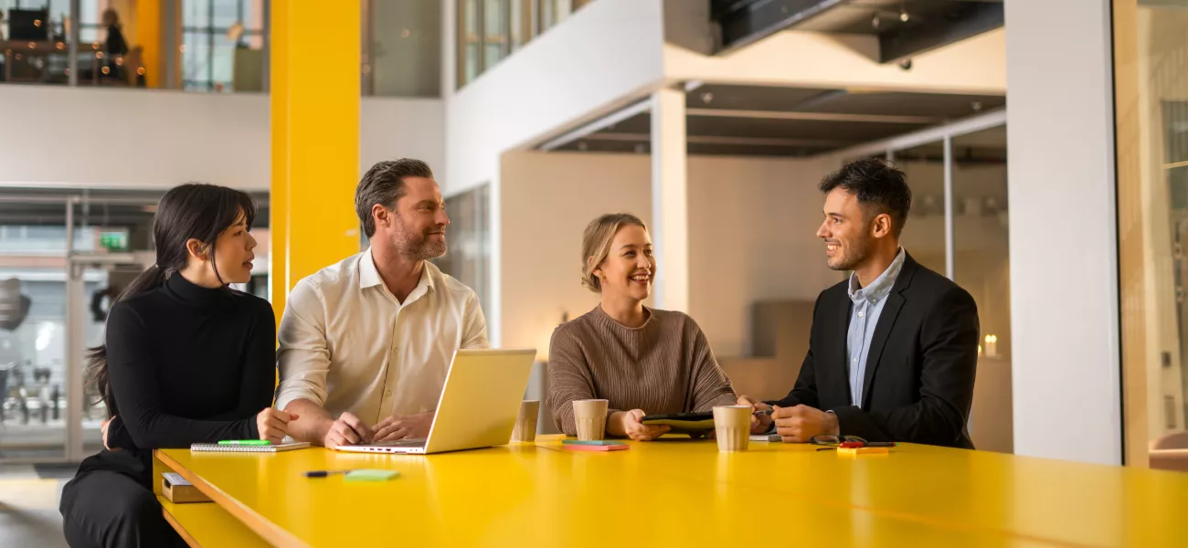 Four people collaborating at a yellow table