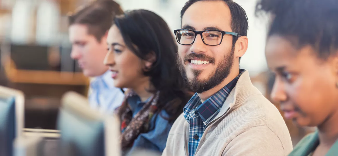 Man in glasses smiling by computer