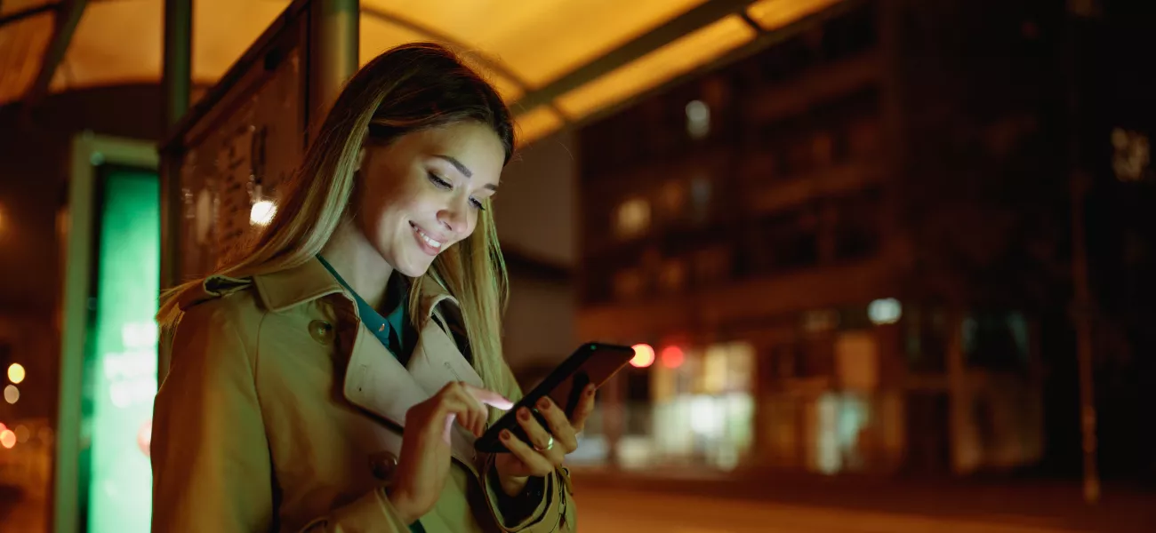 Woman at bus stop at night with phone