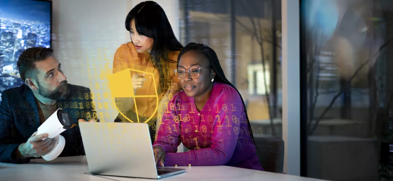 Cybersecurity group sitting around a laptop discussing software support within video surveillance systems