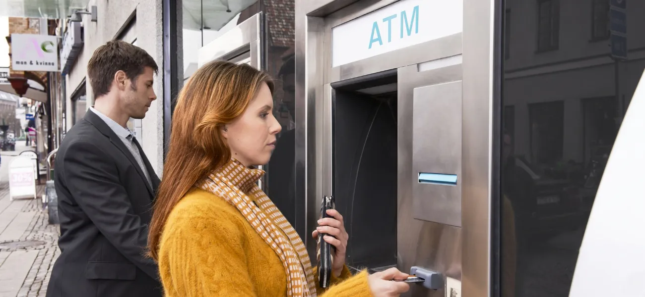 A woman inserts her card into an ATM