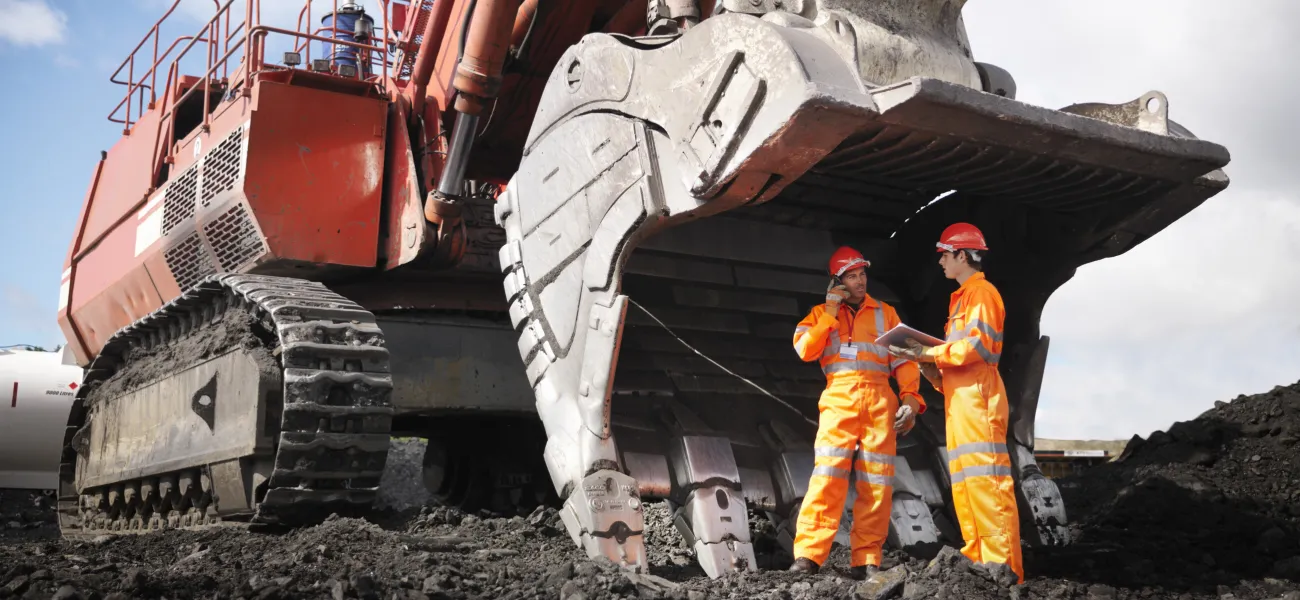 Miners standing on a mining site with a vehicle next to them