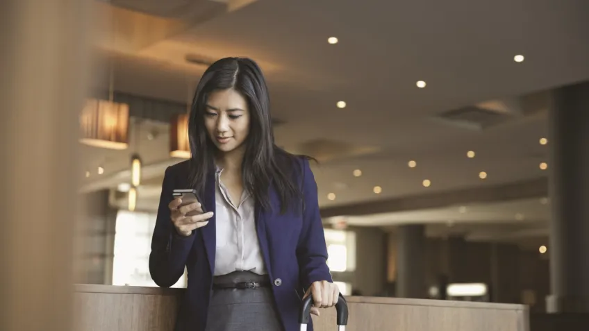 Woman using a mobile phone for online booking in a hotel