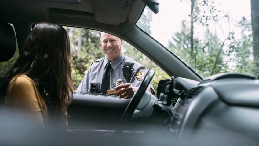 A women in a car that has been stopped by a police officer