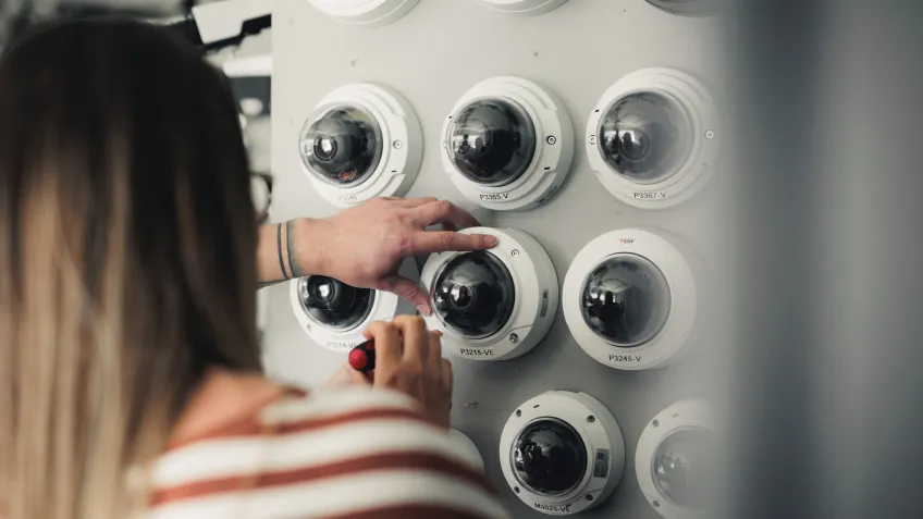 Technical services in front of a wall with multiple dome cameras use for training on how to perform security camera maintenance