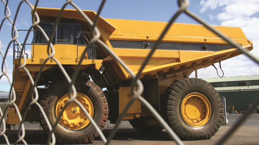 Mining truck passing a fence securing the mining site