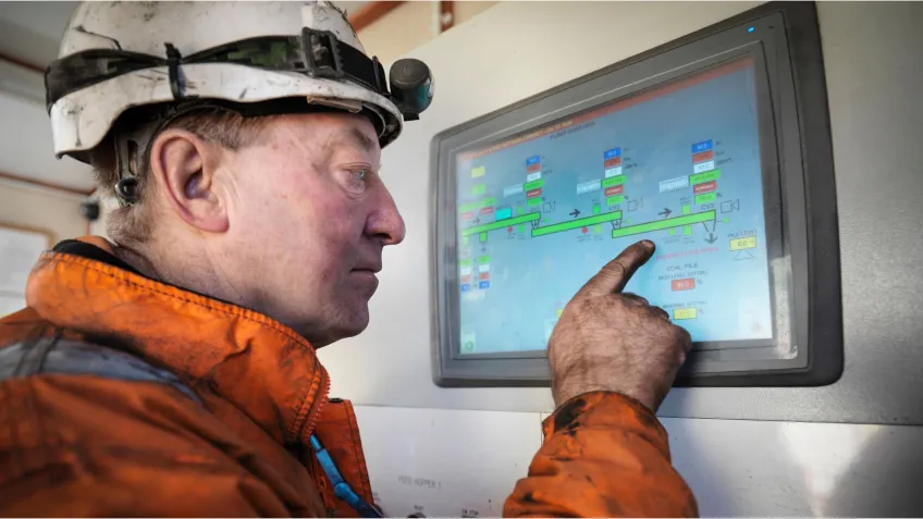 Mine worker looking at a screen showing mining analytics