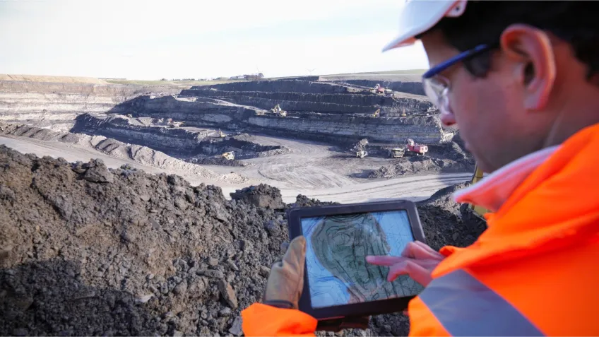 A mine worker using a tablet with a mine overview