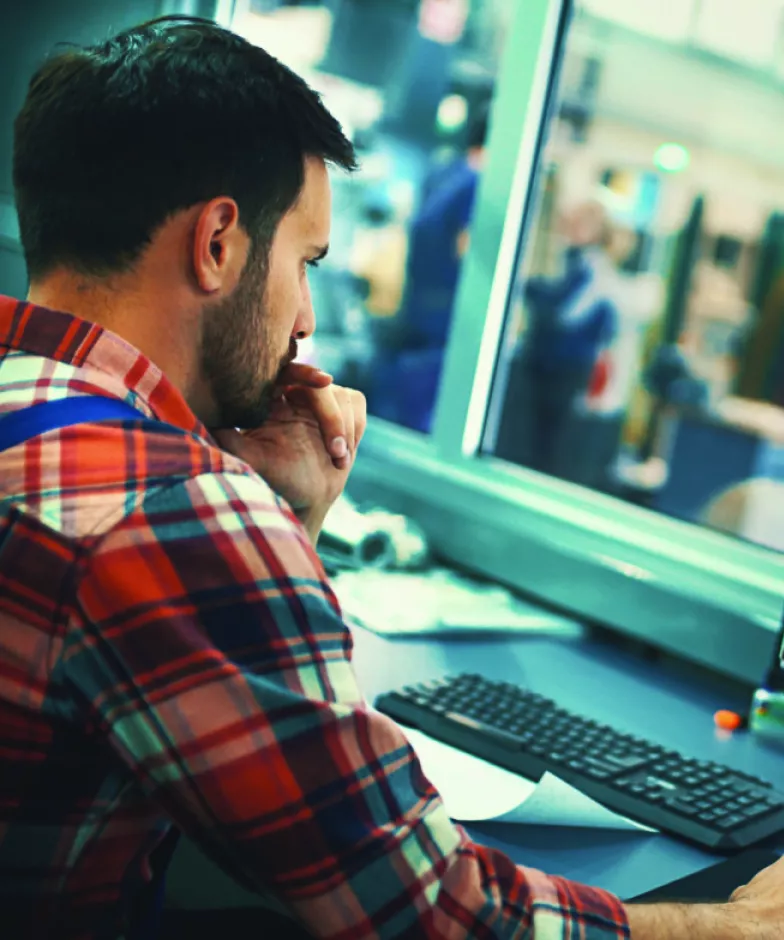 Man in front of a screen showing a production line