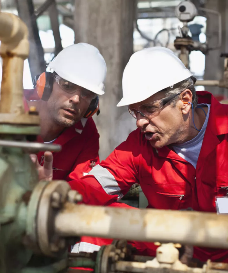 Two workers examining oil equipment